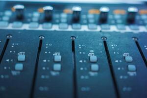Close Up of Professional Audio Mixing Console with Faders and Knobs photo