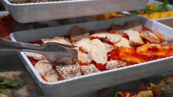 tongs in tray full of meat with sauce and berries in cafe video