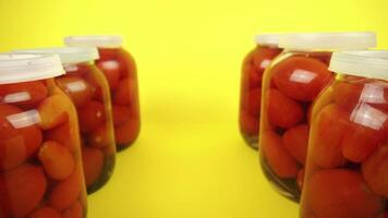 Forward movement lngo closed tomato cans on yellow background video