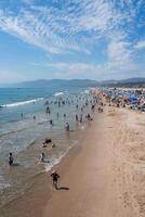 Bustling Scene at Venice Beach with Crowds and Colorful Umbrellas photo