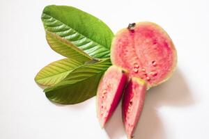 Pink guava with green leaves and slices isolated on white background, top view, flat. photo