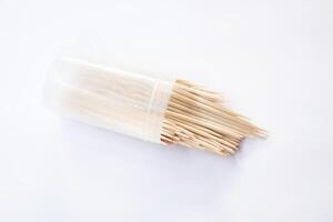 Toothpicks in a container isolated on a white background, A toothpick is a piece of wood, small, short and pointed, It is a tool for removing food particles or dirt between the teeth. Tableware. photo