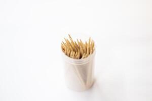 Toothpicks in a container isolated on a white background, A toothpick is a piece of wood, small, short and pointed, It is a tool for removing food particles or dirt between the teeth. Tableware. photo