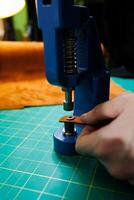 Close-up of the master's hands sewing handmade leather products. A men's tanner connects the parts, creating quality leather accessories. Working process in a leather workshop photo