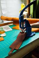 Close-up of the master's hands sewing handmade leather products. A men's tanner connects the parts, creating quality leather accessories. Working process in a leather workshop photo