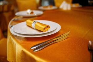 Elegant table setting with fork, knife and gold napkin photo