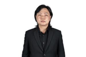 The portrait of a young Asian man wearing the tidy black suit with plain expression on the white grey background shot in the studio. photo