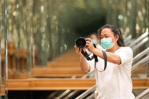 Photographer using camera to taking Self Portrait in the mirror.Photographer with a black SLR camera. photo