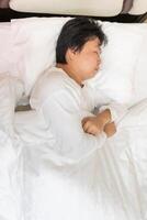 Top view of an exhausted man tosses and turns on a bed all night by restless sleep or insomnia problem. Health issue from anxiety, depression, and stress. photo