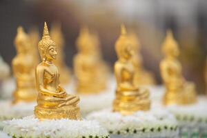 Golden Buddha statue meditation sitting in lotus with blurry Golden Buddha background. Buddha in meditation posture during seated with both hands placed on the lap by right hand over left hand. photo