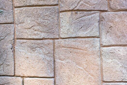 The stone wall is patterned in light brown tones, each cube is different, small and large alternately. photo