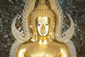 close up of golden Buddha statue is a stunning sight to behold. The intricate details and craftsmanship of the sculpture are clearly visible, showcasing the skill and talent of artist who created it. photo