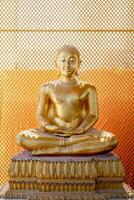 Vintage gold Buddha statue in front of yellow orange grill background with the square pattern light from behind. photo