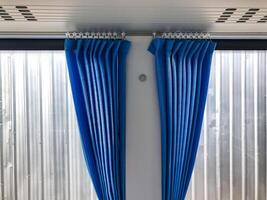 Shot of blue curtains installed on the windows of new air conditioned bus in second layer of white curtains background. photo