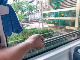 Rear View Of left hand holding handrail inside a bus, public transportation seen through window. photo