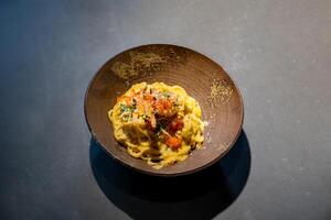 Spaghetti Carbonara pasta Egg and Cheese creamy cream sauce with Shrimp and micro herb decoration on the top of it of earthware circle bowl in studio light. photo
