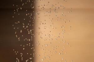 Abstract backgrond dropped water stop motion and dripping to the ground from Shower on blur orange brown background at outdoor light. photo
