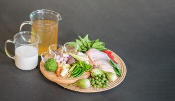 The ingredients, including chicken wings, chilli, kaffir lime leaves and lemongrass, are prepared to be cooked for a famous thai dish, Green Curry. photo