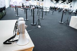 Two white - gray MEGAPHONE are laid on cream table in empty hall, ready to used for event corona virus vaccine booster in Bangkok, Thailand. photo
