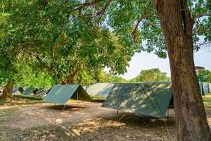 The simple and normal empty Canvas Tents in the row and column on the grass field at outdoor field in afternoon time. photo