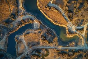 Aerial view of an abandoned quarry with water-filled pits and winding dirt roads. photo