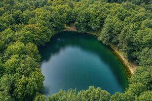Aerial view of a serene, secluded lake nestled within a lush green forest. photo
