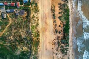Aerial view of coastal houses, beach, dunes, and ocean waves. photo