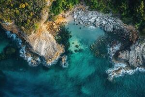 Aerial view of secluded cove with turquoise water, rocky shore, and lush greenery. photo