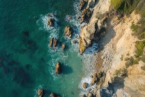 Aerial view of a rocky coastline with clear turquoise water. photo