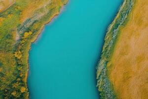Aerial view of a vibrant blue river winding through golden fields. photo