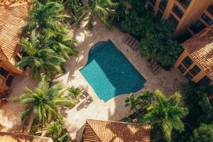 Aerial view of a resort pool surrounded by palm trees and buildings. photo