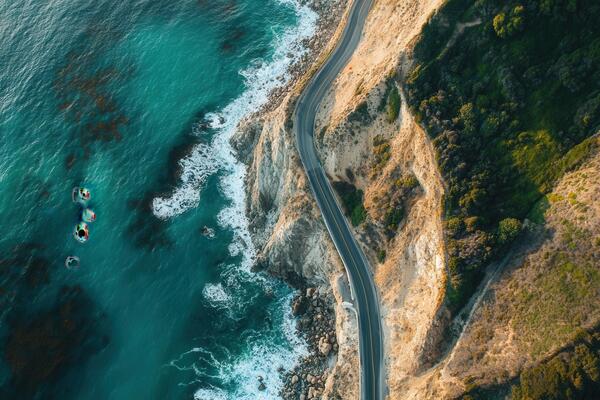 Aerial view of coastal highway winding along dramatic cliffs and ocean.