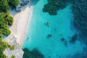 Secluded beach with turquoise water, a boat and swimmer seen from above. photo