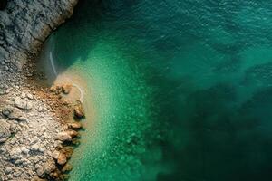 Aerial view of turquoise water meeting rocky shore. photo