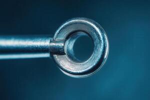 Close-up of a metallic ring on a rod, showcasing its texture and detail against a dark blue backdrop. photo