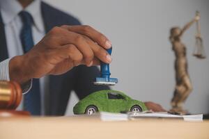 Judge gavel and miniature car symbolize auction or court case against driver who has accident and receiving vehicle insurance payment be on table in front of hands of lawyers. Selective focus photo