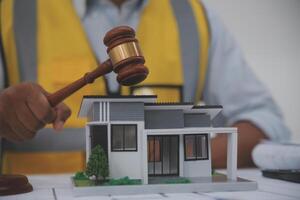 Judge gavel on building blueprint plans with a yellow safety helmet in the background. law that deals with matters relating to building construction, engineering. Construction law concept. photo