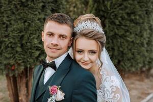 A bride and groom are posing for a picture in front of a tree photo
