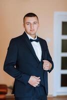 A man in a suit and tie is standing in front of a white door photo