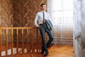 A man in a suit and tie stands on a staircase photo