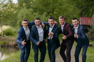 A group of five men in suits are posing for a picture photo