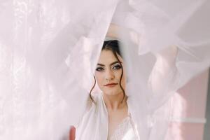 A woman is standing in front of a curtain, with her face partially hidden photo