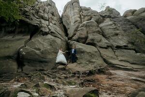 A couple is standing in front of a large rock formation photo
