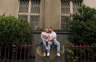 A couple is kissing in front of a building with a fence photo