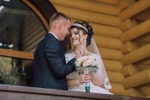 A bride and groom are standing on a balcony, smiling at the camera photo
