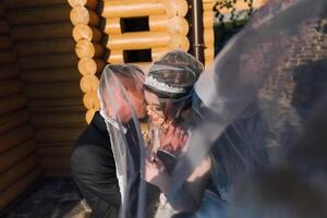 A bride and groom are hugging each other with a veil between them photo