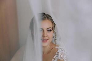 A bride is standing in front of a curtain, with her face partially hidden photo