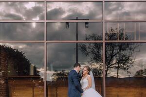 A bride and groom are standing in front of a large window photo