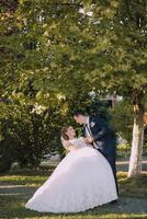 A bride and groom are standing under a tree photo