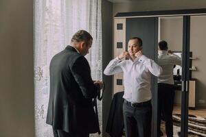 Two men are getting ready for a formal event photo